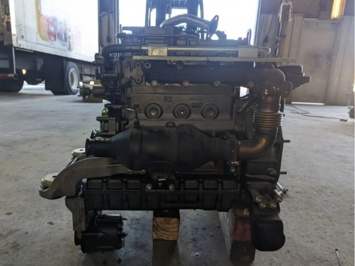 Complete diesel engine pulled from a truck and set on blocks in the shop with a reefer trailer behind it