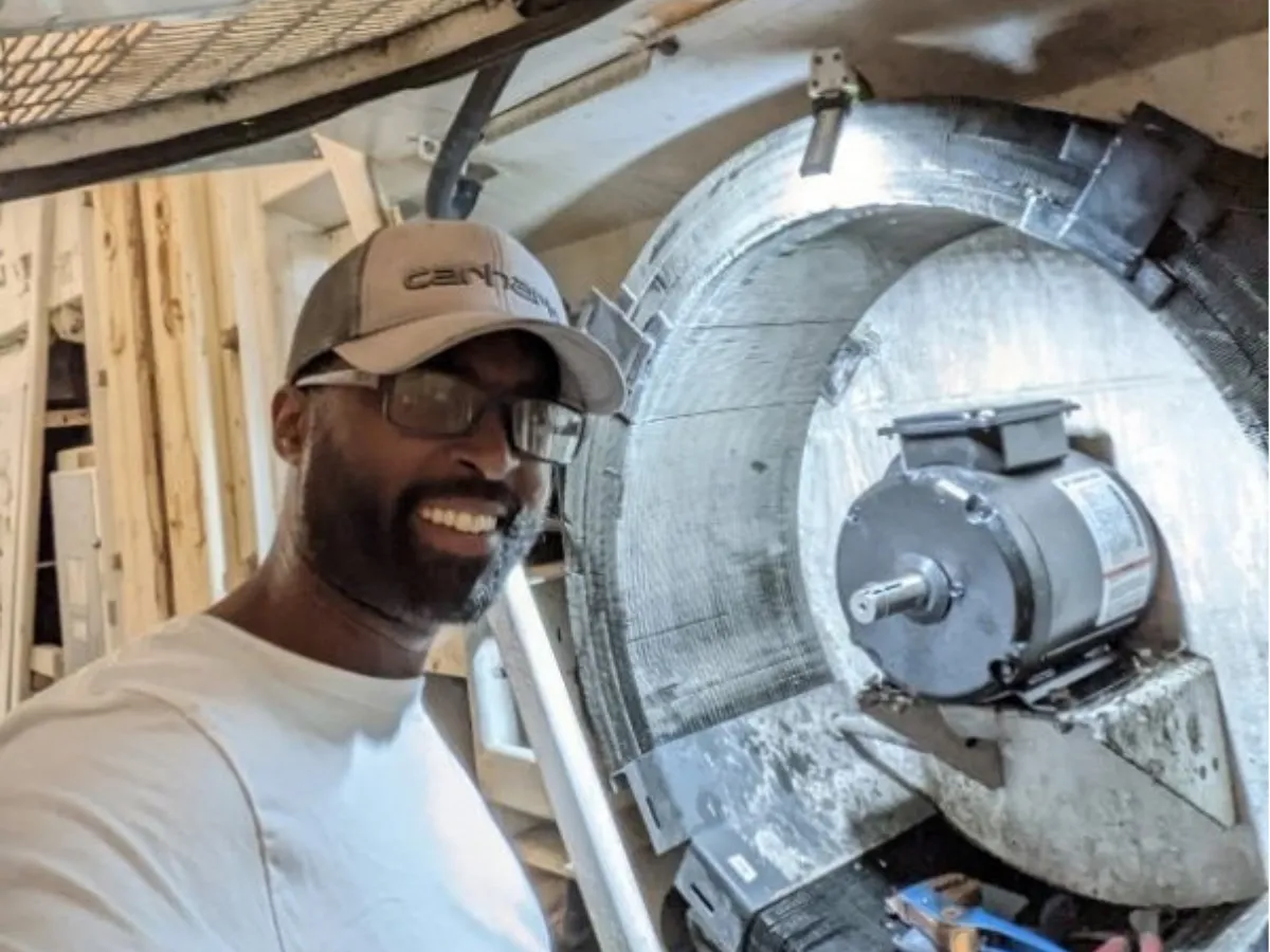 Smiling technician beside a new evaporator fan motor mounted inside a refrigerated box