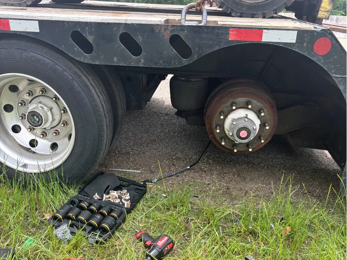 Trailer hub with the wheel removed and impact tools laid out for an on-site tire change