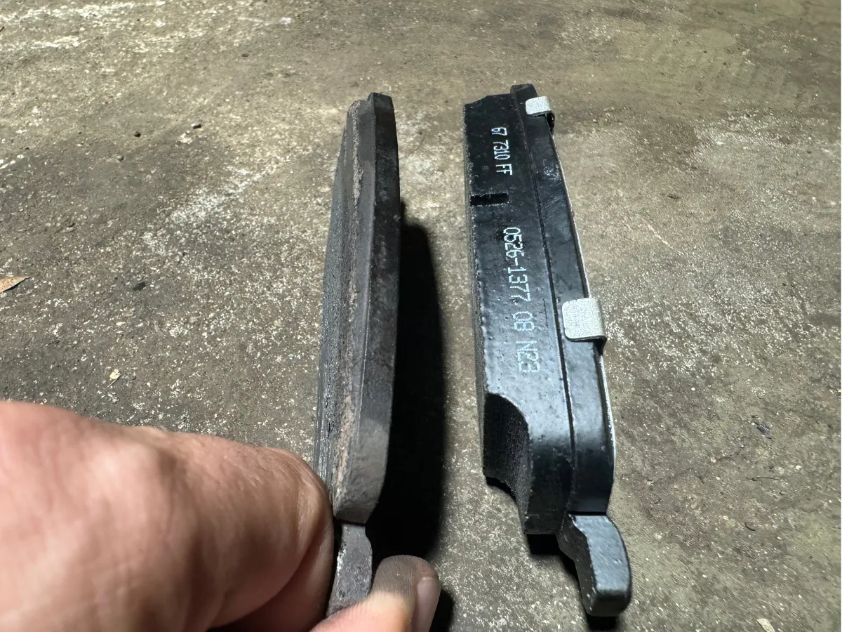 A worn brake pad next to a new brake pad, showing the difference