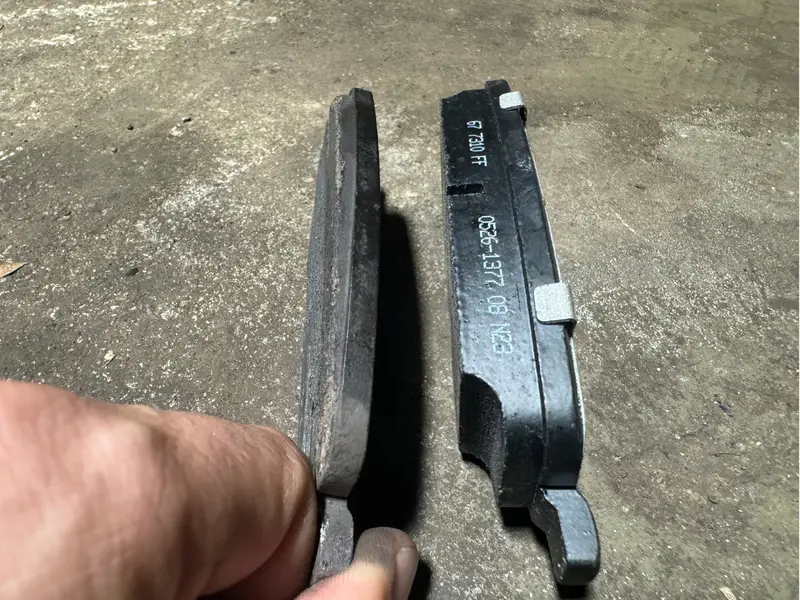 Brake pad inspection showing worn vs new brake pads